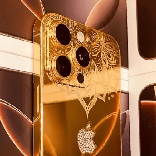 Close-up of a gold-finish phone with floral engraving and a rhinestone Apple logo