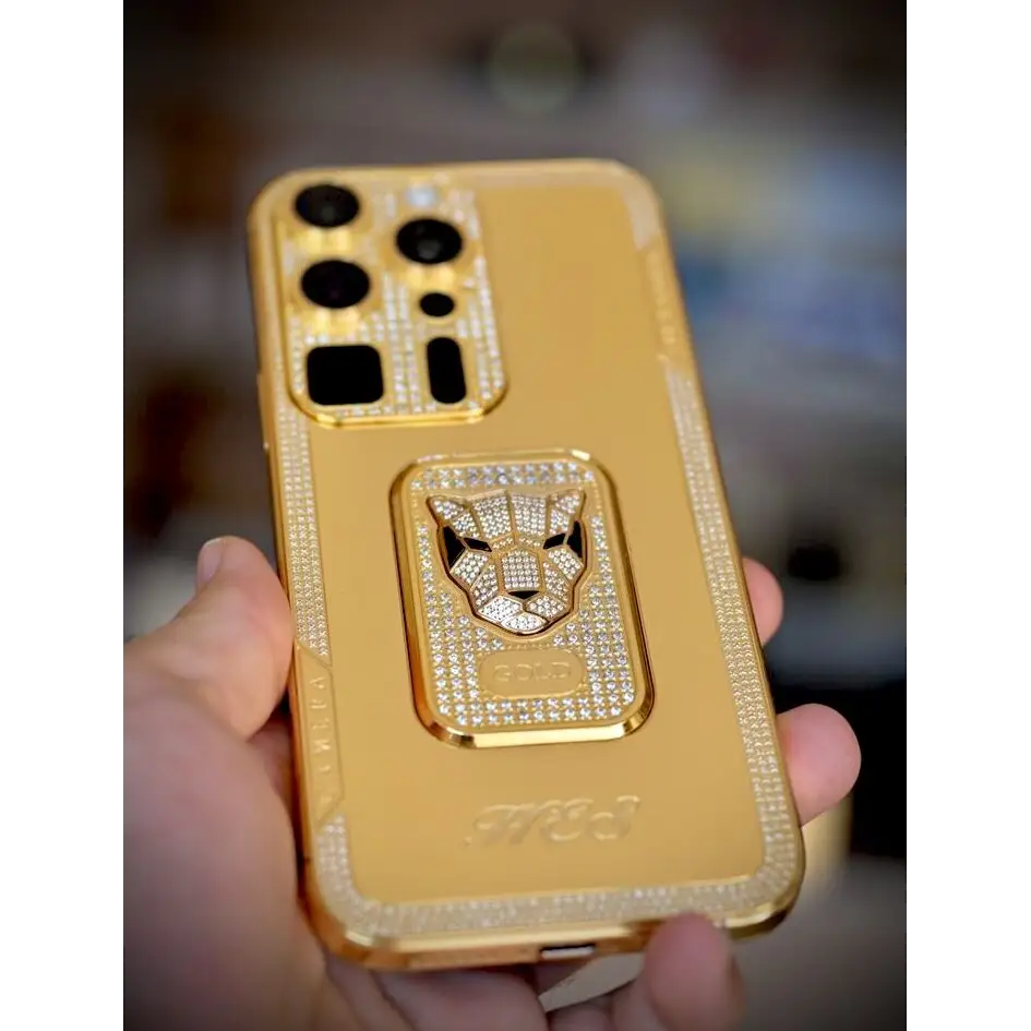 Gold-finish phone with a panther emblem and rhinestone borders, rear view held in hand