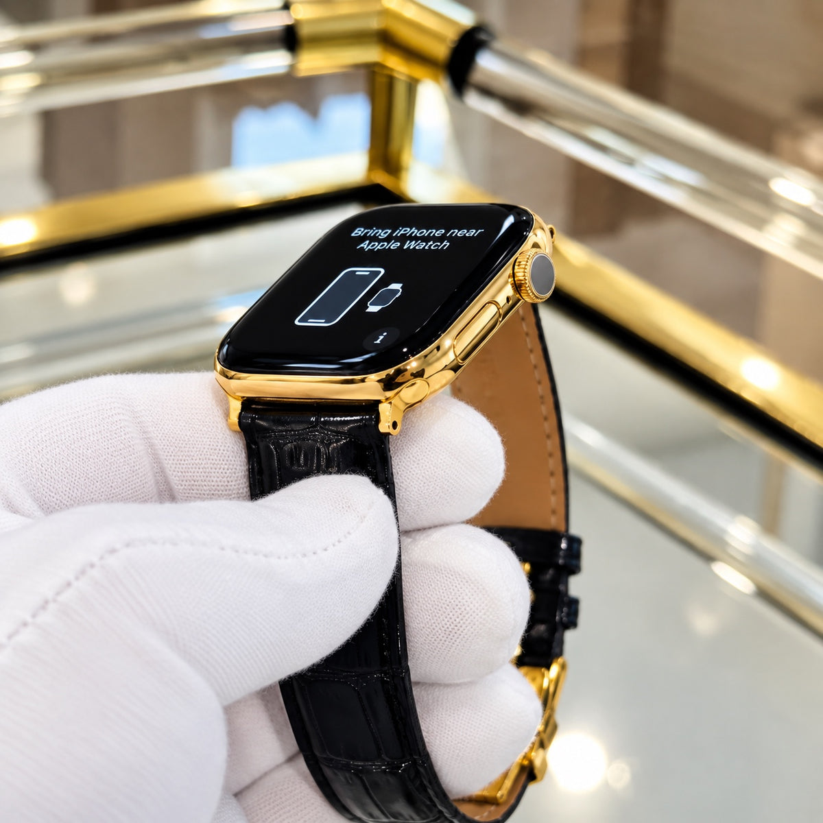 Custom 18K gold Apple Watch Series 12 with black alligator leather band held in a white glove