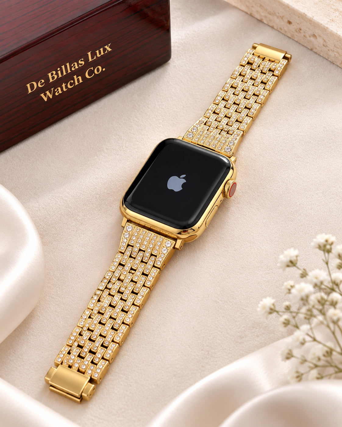 Custom gold Apple Watch and rhinestone link band laid flat beside a De Billas Lux presentation box