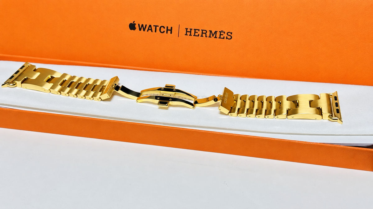 Custom 24K yellow gold plated Hermès Grand H 46mm stainless steel Apple Watch band — digitally edited finish preview, full band with original Hermès box