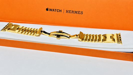 Custom 24K yellow gold plated Hermès Grand H 46mm stainless steel Apple Watch band — digitally edited finish preview, full band with original Hermès box