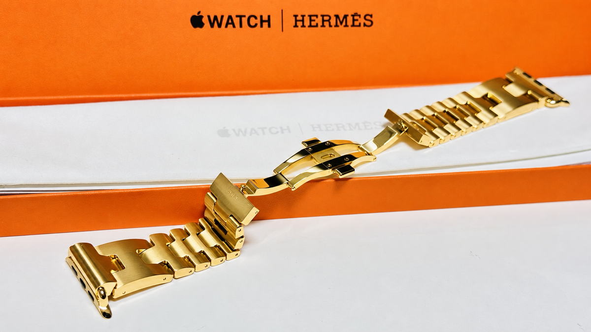 Custom 24K yellow gold plated Hermès Grand H 46mm stainless steel Apple Watch band — digitally edited finish preview, diagonal full band with open clasp