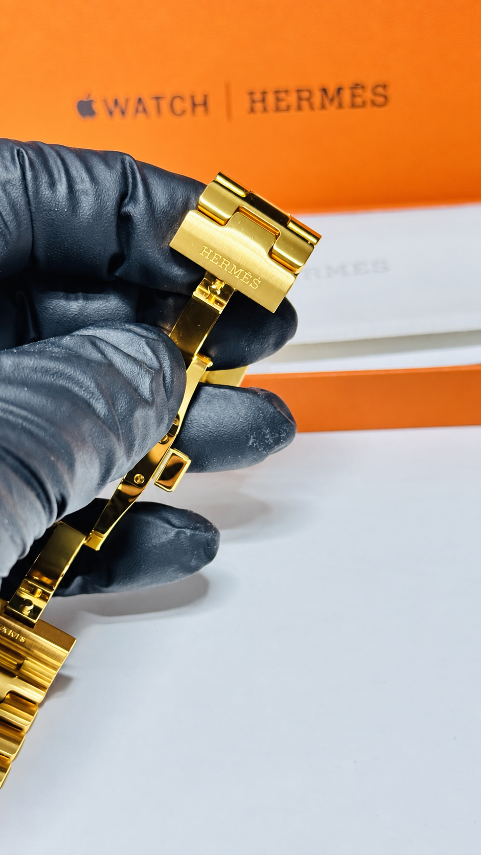 Custom 24K yellow gold plated Hermès Grand H 46mm stainless steel Apple Watch band — digitally edited finish preview, Hermès engraving detail